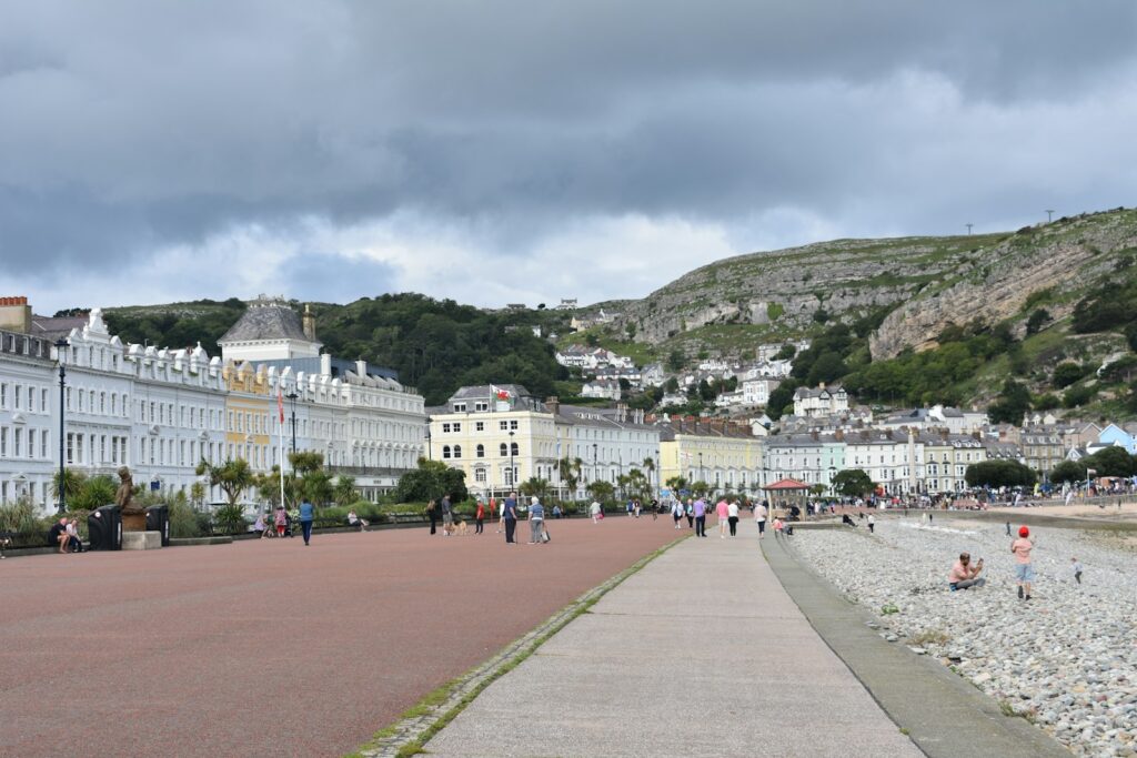 People walking along a street beside a hill in the seaside resort of Llandudno