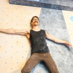 Man bouldering on a colourful indoor climbing wall with differently coloured holds
