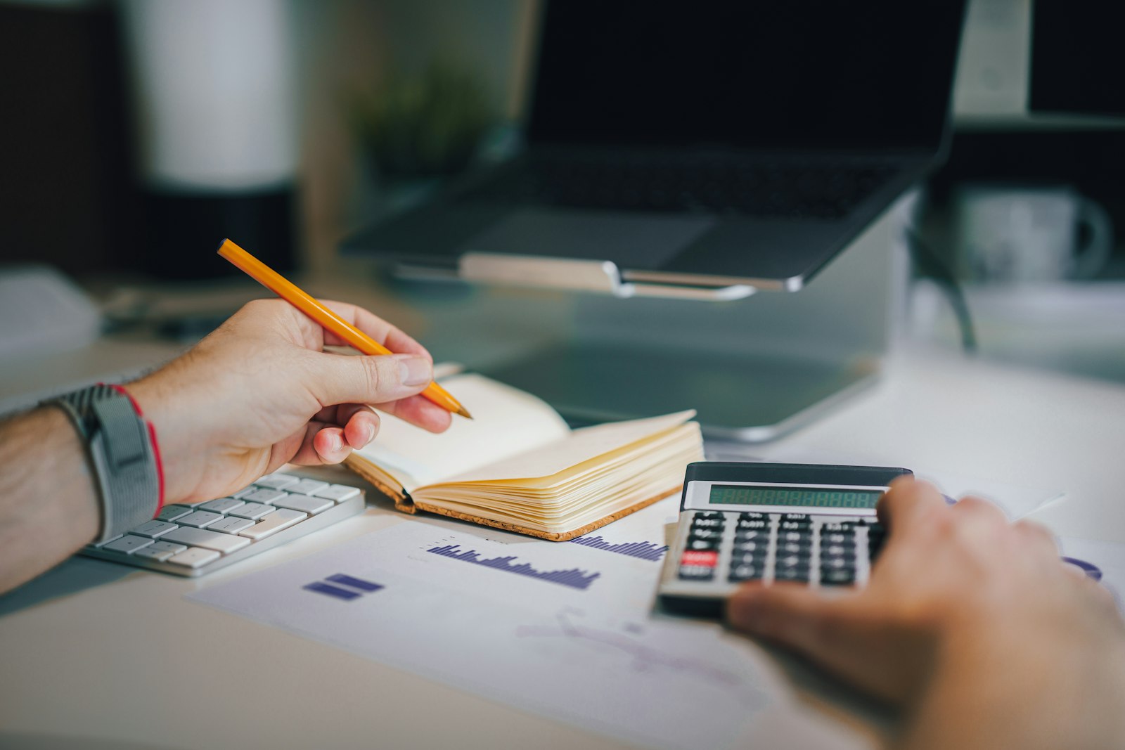 Person sitting at a desk with a calculator and notebook, working through business finances