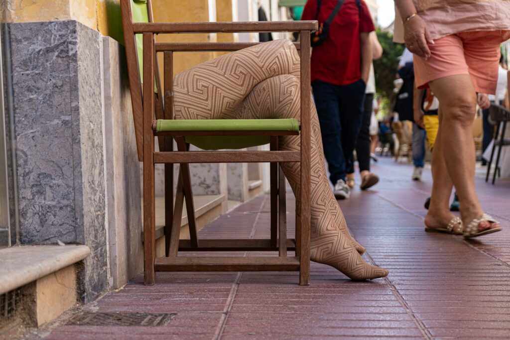 Woman's legs in patterned tights while seated on a chair, showing a bold tights trend