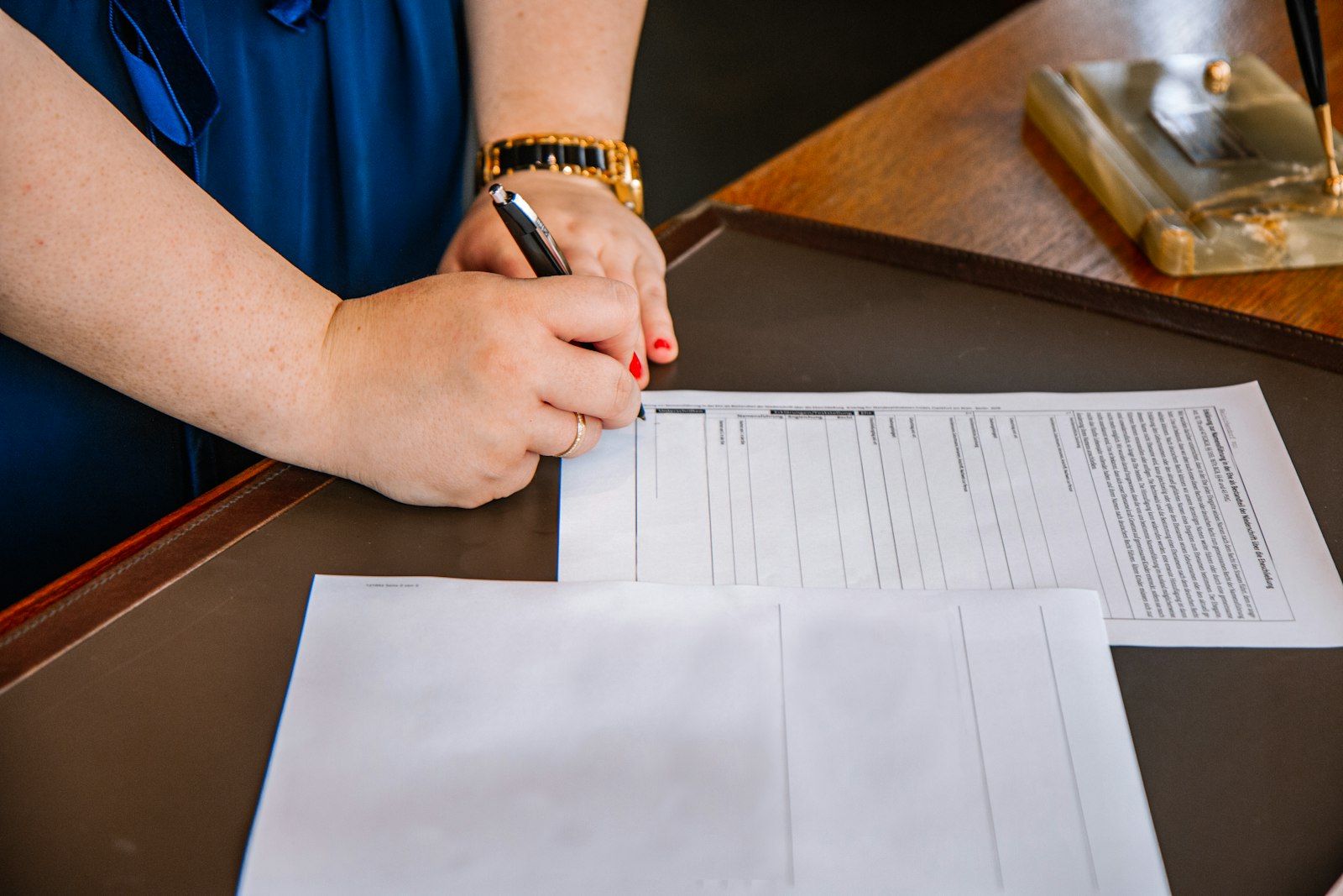 Person holding a pen and writing on paper, much like completing an application form